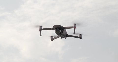 Hovering drone flying upward on a cloudy sky backdrop