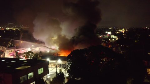 Los Angeles / United States - 06 03 2020: Aerial, drone shot towards a Starbucks building in flames, arson, during riots Los Angeles, Fairfax, Santa Monica, California, USA