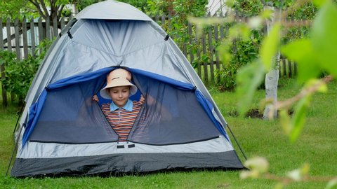 Little boy at camping in summer. Child is playing in a tent.