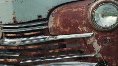 Abandoned rusty vintage car with peeling paint, close up