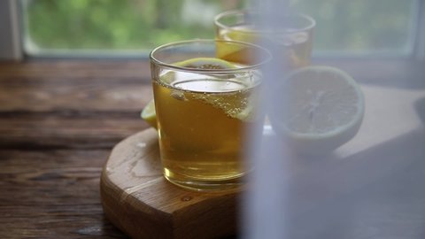 Cold tea or fermented raw kombucha with lemon at summer day. The tulle sways in the wind