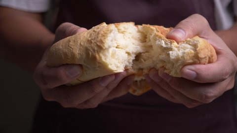 Male hands breaking fresh bread in slow motion
