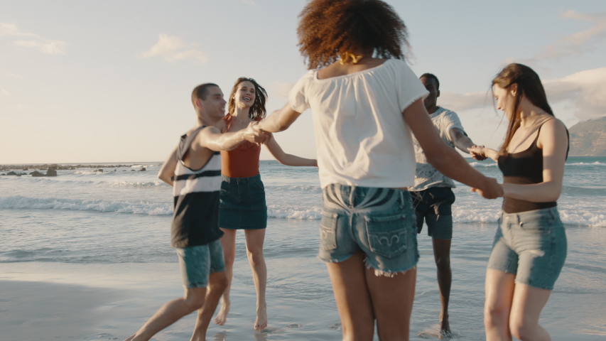 Group of friends playing with holding hands on the beach. Men and woman playing ring around the rosy on the sea shore.
 Royalty-Free Stock Footage #1054408310