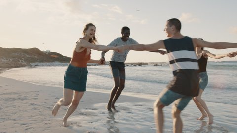 Group of friends playing with holding hands on the beach. Men and woman playing ring around the rosy on the sea shore.

