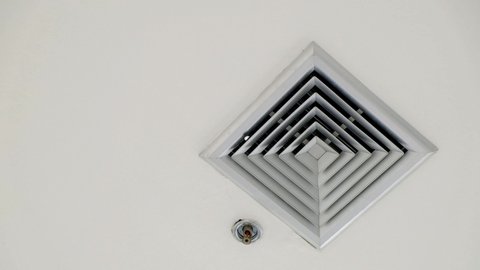 Air vent on a ceiling, pans to air vent cover on office ceiling, Plastic ventilation grid, piece of home ventilation system.