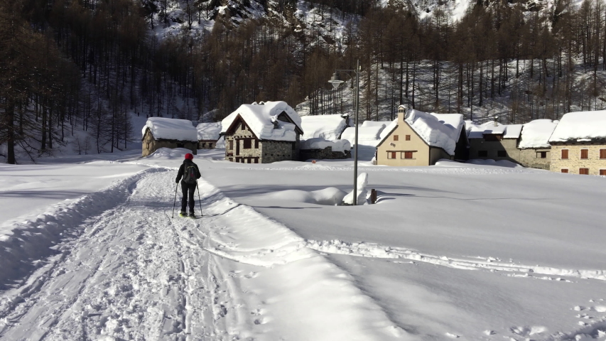 A hiker walks with snowshoes in the enchanting landscape of Alpe Devero in Piedmont Italy.