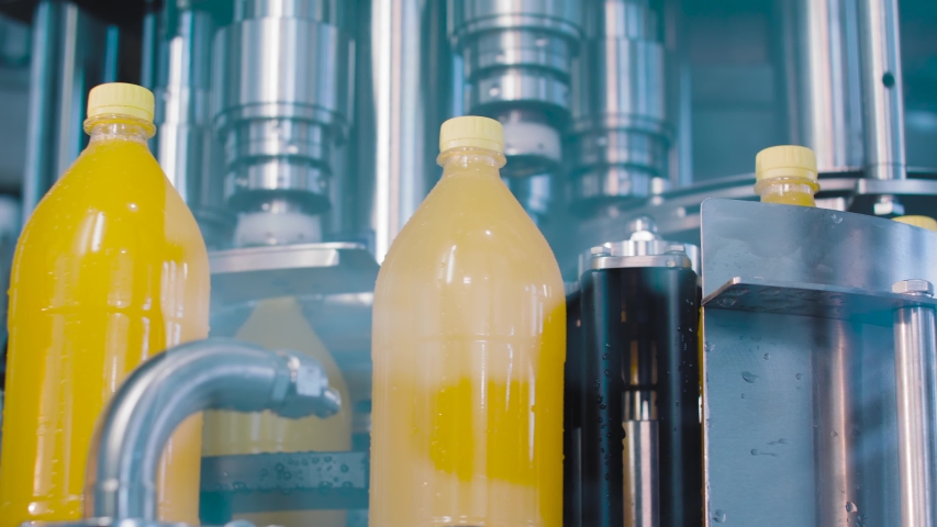 The new plastic bottles on the conveyor belt at the juice factory. Production and bottling of beverages carbonated lemonade, soda or beer in plastic bottles on automatic conveyor on industrial plant.  Royalty-Free Stock Footage #1054410836