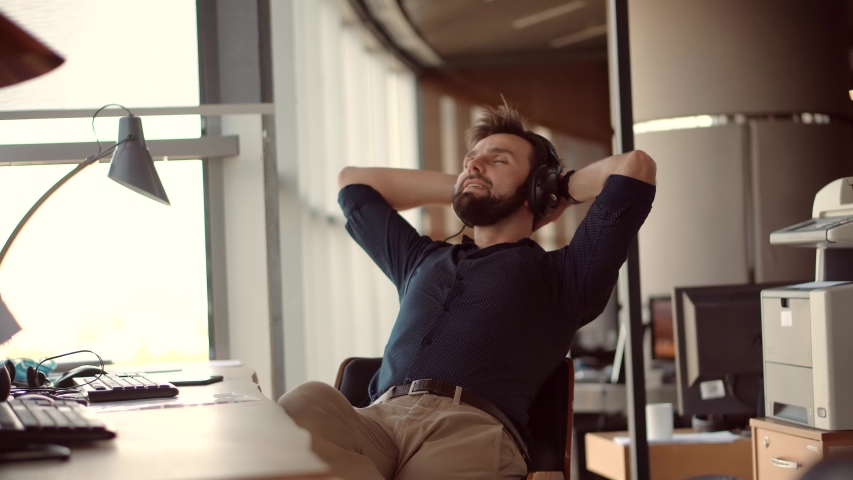 Thoughtful Serious Man Sitting On Workplace And Listening Podcast.Happy Healthy Stress Free Man Relaxing In Office And Listening To Music.Employee Taking Break On Work.Businessman Leisure In Headphone | Shutterstock HD Video #1054416383