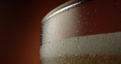 Froth Beer Pouring Out from a Glass a Macro Shot on Red Epic with Terra Cotta Background