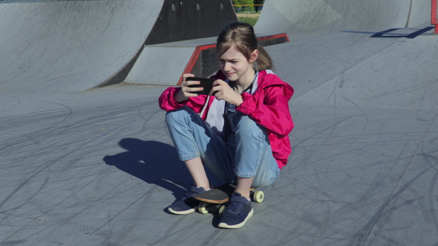 Girl using smartphone on the ramp for extreme sports