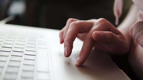 The woman's hand uses the trackpad of the modern laptop sculpting of the computer with special multi-touch gestures. Shallow deph of field, close up, gimbal shot.
