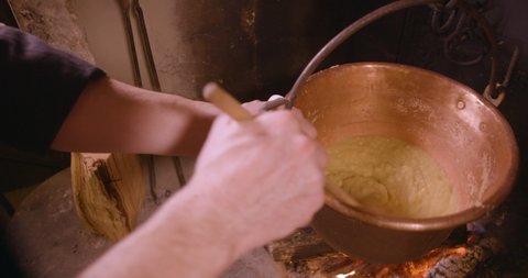 Polenta, traditional cornmeal of Northern Italy. Professional cook preparing food in restaurant kitchen. Man at work as chef and cooking