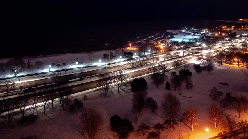 Beautiful zoom out aerial morning sunrise timelapse of the Chicago Lakefront along Lake Michigan with traffic flying by on Lake Shore Drive as night turns to day.
