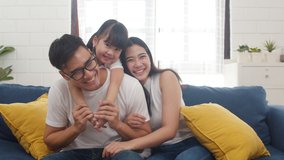 Happy cheerful Asian family dad, mom and daughter having fun cuddling and video call on laptop on sofa at house. Self-isolation, stay at home, social distancing, quarantine for coronavirus prevention. - Powered by Shutterstock - Get 15% off with code: PIKWIZARD15