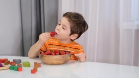 Smiling boy at breakfast eating fruit strawberries. stock footage. Slow Motion video. Close up