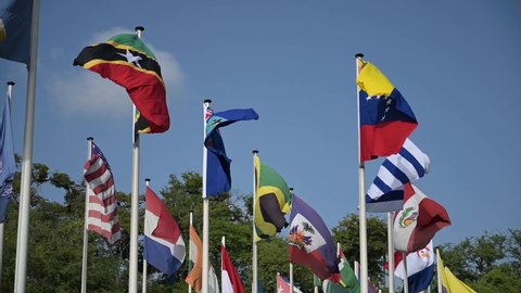 Flags of Belize, India, Jamaica, Saint Kitts and Nevis, Saint Lucia, United States of America, Uruguay and Venezuela on a set of flag poles in slow motion