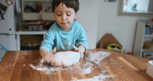 A boy and a woman kneading and pressing pizza dough on a floured surface.