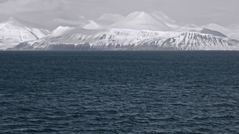 Isfjorden fjord in the Arctic ocean, view from the water of the mountains covered in ice and snow.