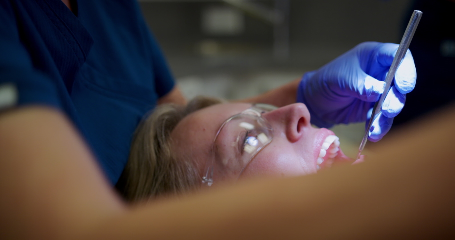 CU SELECTIVE FOCUS Dentist examining teeth of patient at dentist's office, Hove, Sussex, UK Royalty-Free Stock Footage #1054441700