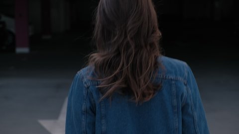 Rear Back View Of Girl Going Forward. The Girl Wearing Jean Jacket and Black Jeans. Summer Evening