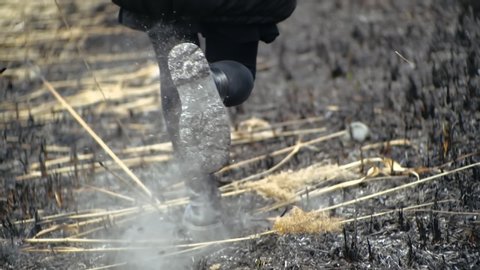 Cinematic shot from behind of running female legs in leggings and in stylish black high-soled shoes over burned ash grass of field after fire. Jogging girl among ashes. Woman run away.