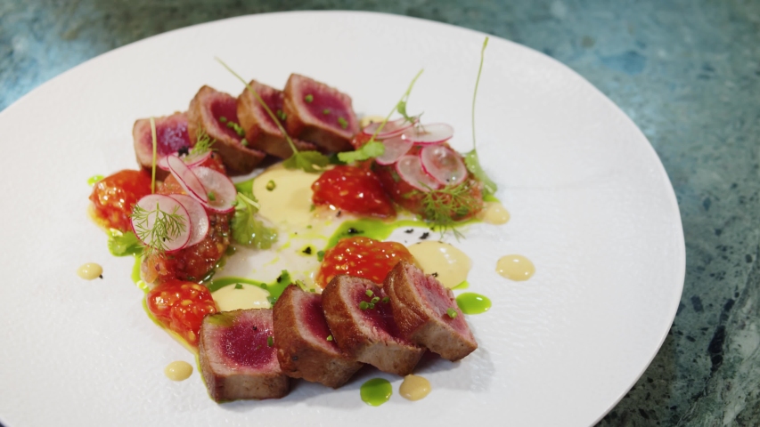 Elegant woman eating tuna steak with colorful salad in high kitchen restaurant, haute cuisine, fine dining in a professional gourmet kitchen Royalty-Free Stock Footage #1054444538