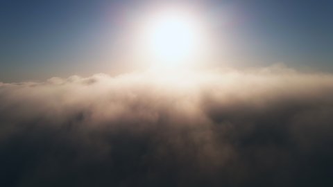 Moving white clouds blue sky scenic aerial view sunrise. Drone flies high back in blue sky through fluffy clouds in morning at bright sun summer. Sun is hidden behind clouds at fog. Relax. Nature