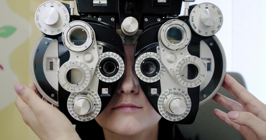 Eyesight measurement to young woman with optical phoropter. Woman doing eye test Slow motion Close up Royalty-Free Stock Footage #1054448453