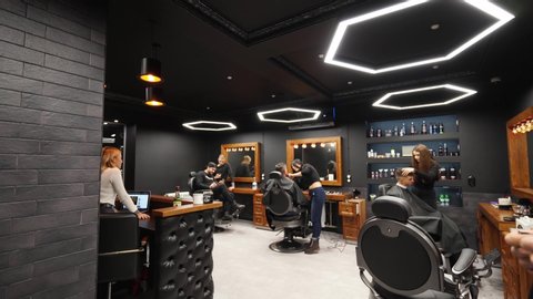 Point of view shot of hipster barber throwing a hair cloak on the client with transition to black. Hairdresser puts on cape on camera in barber shop, POV. Trendy coiffeur at work in retro hair salon.