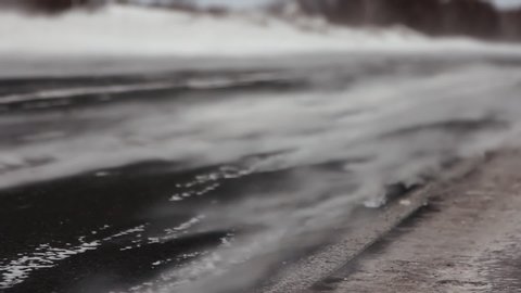 Close-up of Asphalt on Northern Motorway. Strong Snowstorm. Snow Sweeps Road. Wind. Cold weather. Road of life. Blowing snow. Only Road Leads to Village in Tundra. Danger of Freezing. Severe Frost
