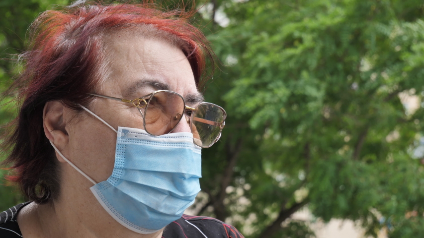 An elderly woman in a respiratory protective mask on the street. Quarantine Coronavirus Covid-19 for the elderly. Retirement Health at Risk, Grandma in Medical Mask