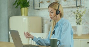 Beautiful Young Caucasian Woman Wear Headphone Communicating Video Conference Call Speak Looking at Computer Home Office Concept Interview Call Center Helpdesk Slow Motion Quarantine Job.