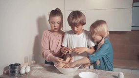 Cute blond children prepare pie dough in the kitchen. Bright kitchen.