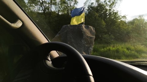 Ukrainian flag is developing in the wind view from the SUV