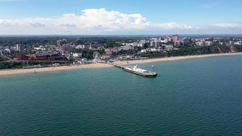 Aerial drone footage of the Bournemouth beach, Observation Wheel and Pier on a beautiful sunny summers day with lots of people relaxing and sunbathing on the British Dorset sandy beach and ocean