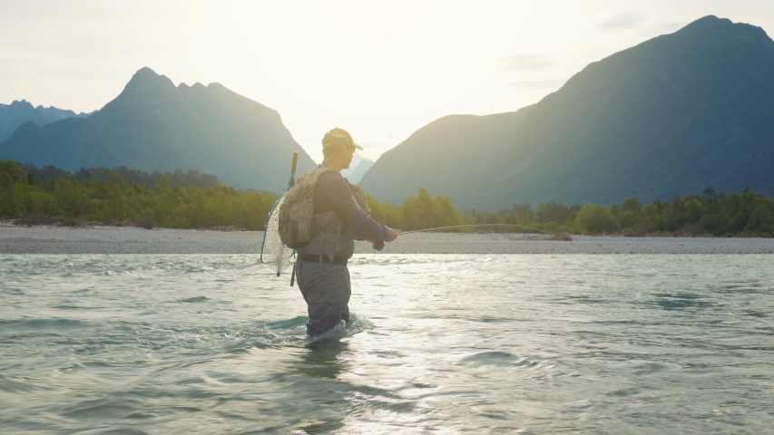 A fully equipped fisherman swinging the fishing line to cast salmon on a sunny morning Royalty-Free Stock Footage #1054477613
