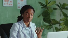 Afro-american friendly female doctor talking on laptop webcam explaining diagnosis remotely to distant client via online videochat telemedicine consultation. Hospitals. Medical staff.