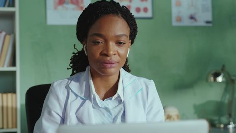 Afro-american friendly female doctor talking on laptop webcam explaining diagnosis remotely to distant client via online videochat telemedicine consultation. Hospitals. Medical staff.