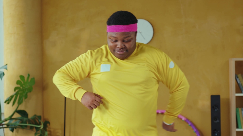 Fat handsome retro style young man dancing into music, doing warm-up exercises aerobics session training at home. Workout. Sports beginner. Funny activity. Royalty-Free Stock Footage #1054478015