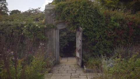 Walking through old country gardens to an overgrown historic stone gateway