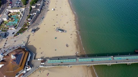 Aerial drone footage of the Bournemouth beach, Observation Wheel and Pier on a beautiful sunny summers day with lots of people relaxing and sunbathing on the British Dorset sandy beach and ocean