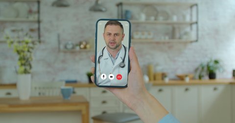Beautiful woman checks possible symptoms with professional physician, using online video chat. Young girl sick at home using smartphone to talk to her doctor via video conference medical app.