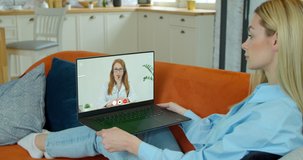 Woman checks possible symptoms with professional physician, using online video chat. Young girl sick at home using laptop to talk to her doctor via video conference medical app.