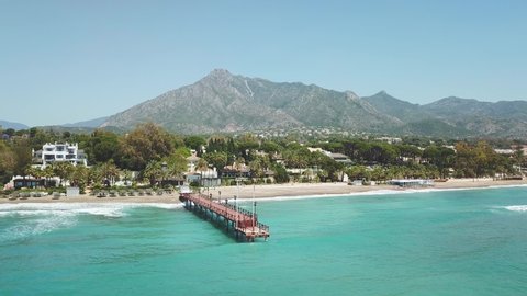 Panoramic aerial view of Casablanca beach Marbella, Famous destination with luxury proprieties and restaurants. View of  wood bridge Puente Romano and mountain La Concha. Drone making a right rotation
