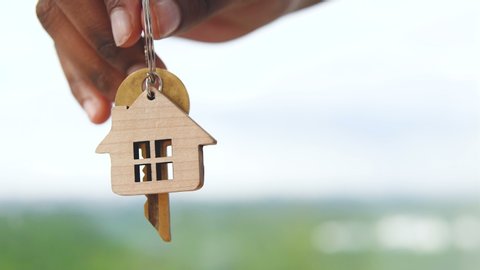 Hand holding out key from house, moving to new home, housing loan service