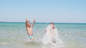 Children play in the purest azure sea on a Sunny day, creating a splashing, splashing slow-motion video. Entertainment and outdoor games in the fresh air.
