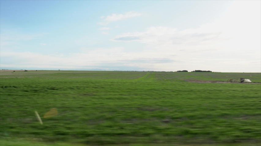 A drive by along recently planted fields  with large metal grain silos on the Canadian prairies in Alberta Canada highlighting the agriculture industry.