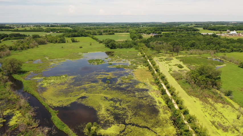 Aerial view of open water marsh and recreational trail through it. Midwestern landscape, wilderness from above. Daytime, summer