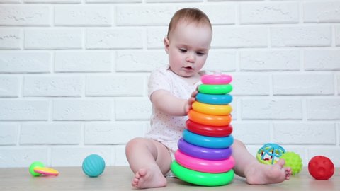 Cute baby girl playing with colorful pyramid toy. Smart funny child. Top view