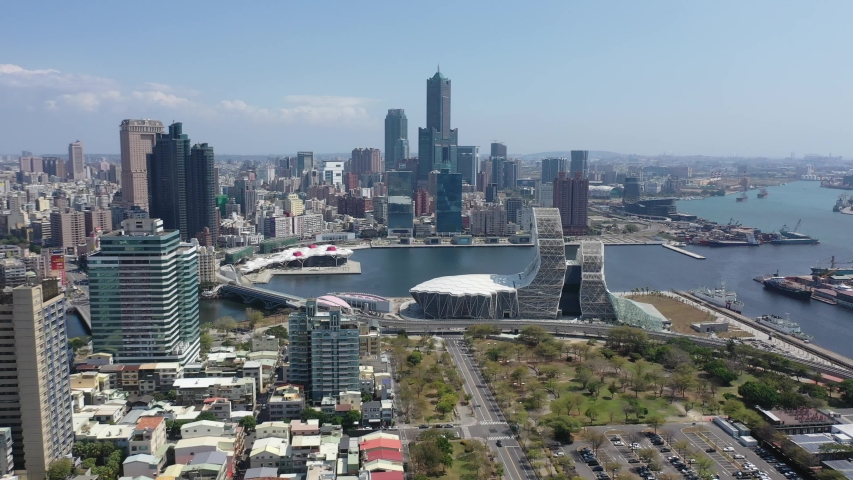 Aerial skyline of Kaohsiung, a vibrant seaport city in Southern Taiwan, with 85 Sky Tower among skyscrapers by the harbor & the futuristic architecture of Music Center by the Love River under blue sky